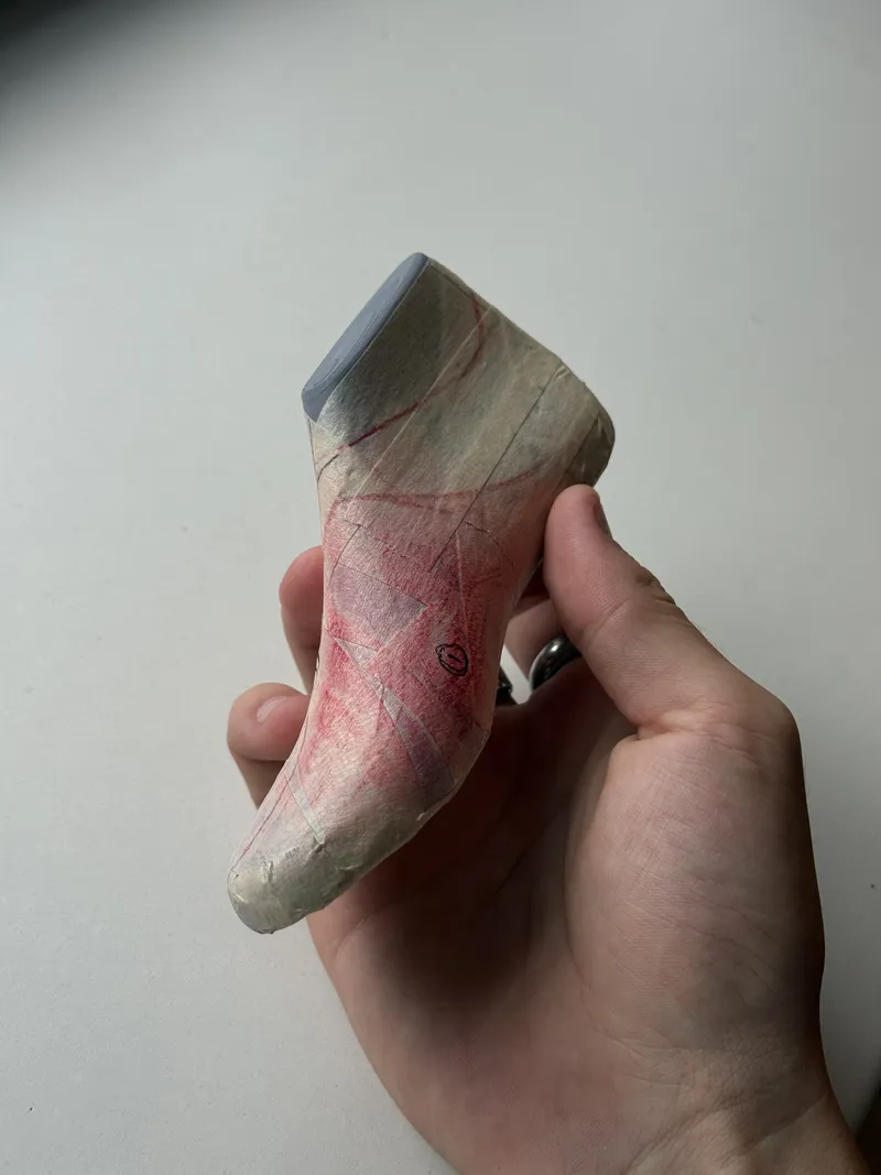 Taped shoe last with pattern lines, held in hand