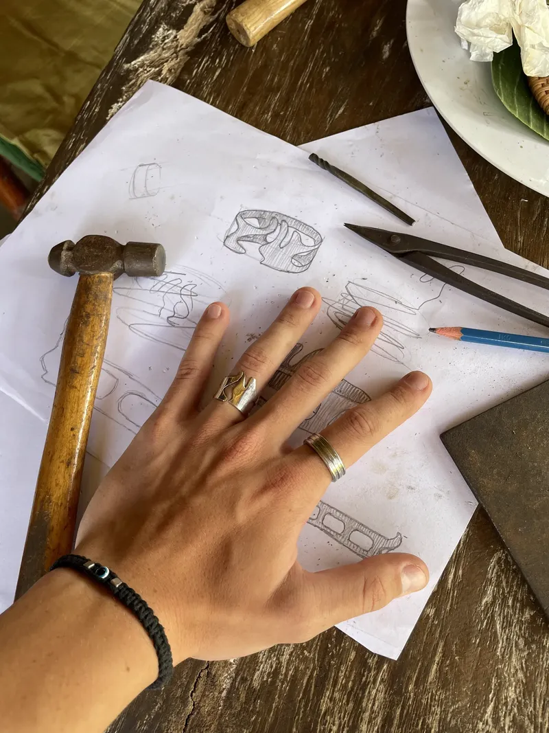 Hand resting on sketches next to a hammer